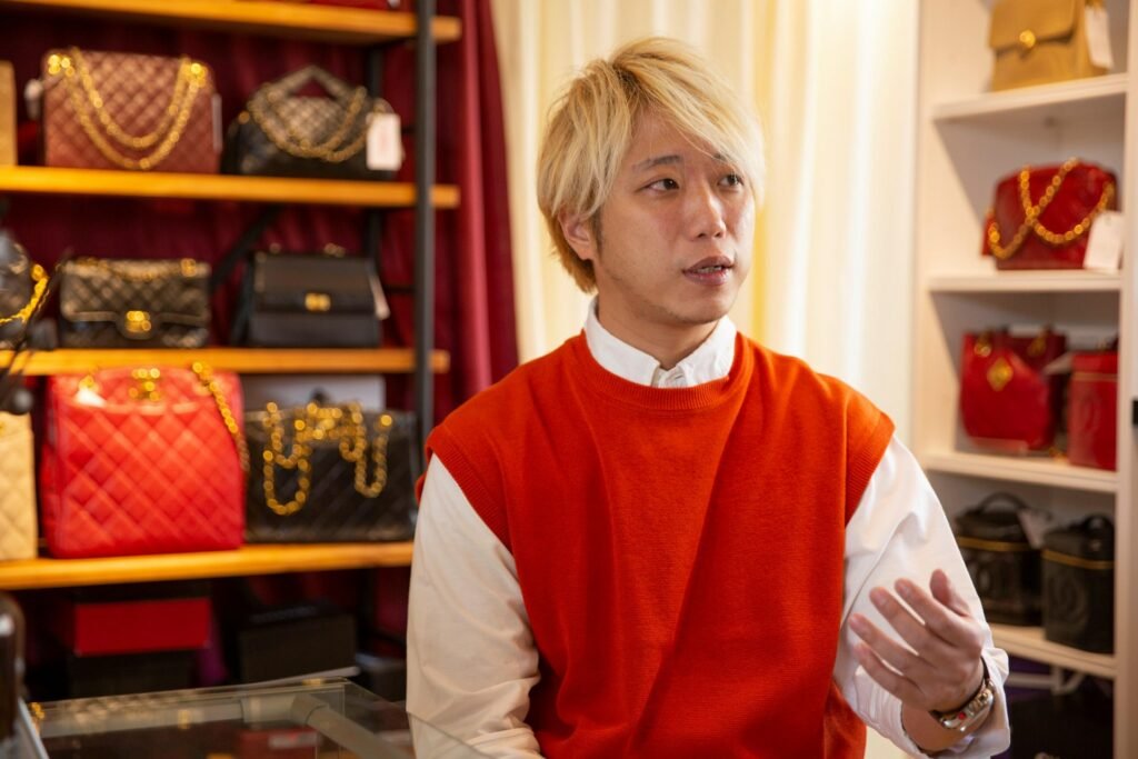 Lovintage founder Shiken explaining vintage bag care with Chanel bags on display behind him